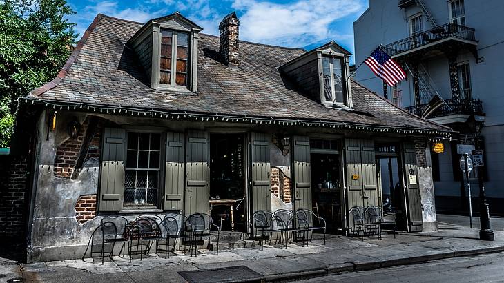 A small old building with anAmerican flag and chairs out the front