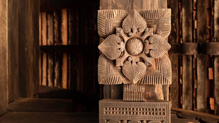 An intricate carving of a square flower on a wooden pillar