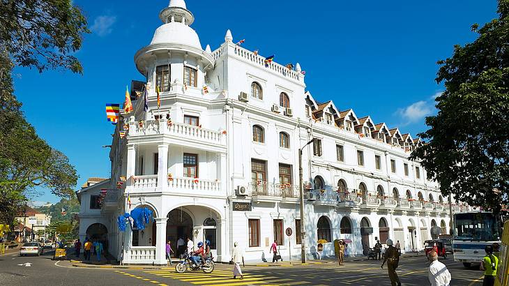 A British colonial-style building across a street with people and a bus