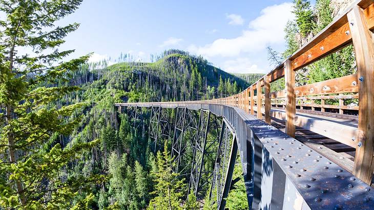 A wooden railway trestle bridge high above a forest underneath a clear blue sky