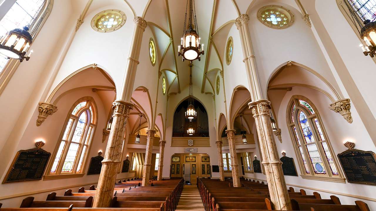 The interior of a religious building with pews and stained glass windows