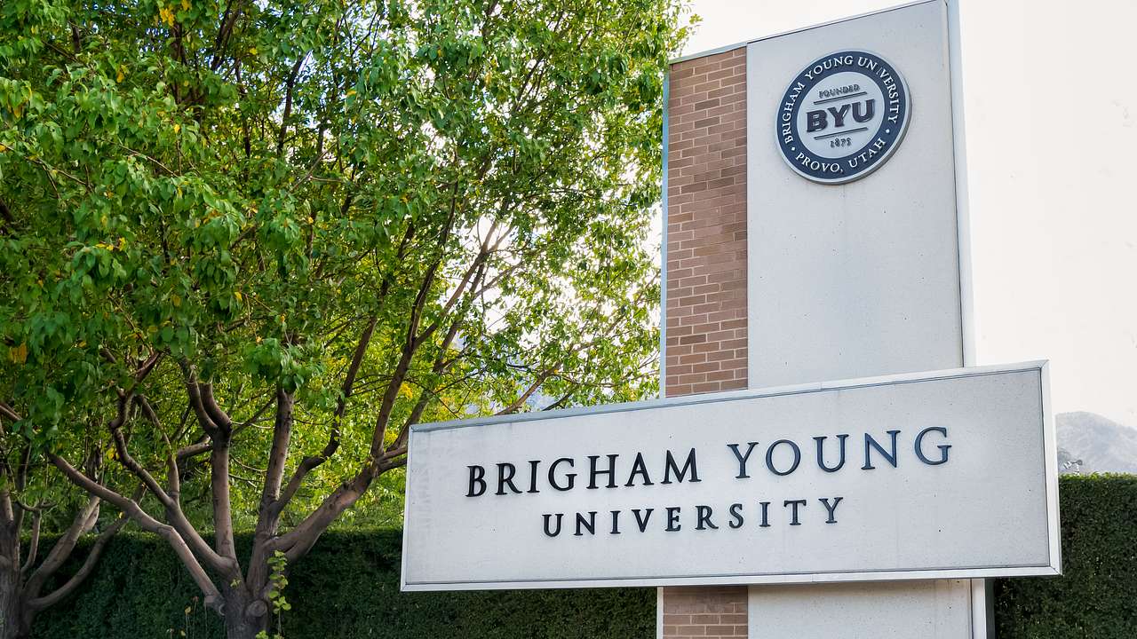 A building with a "Brigham Young University" sign next to a tree