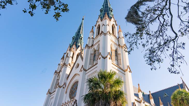 A white cathedral building with two towers and gold and green details