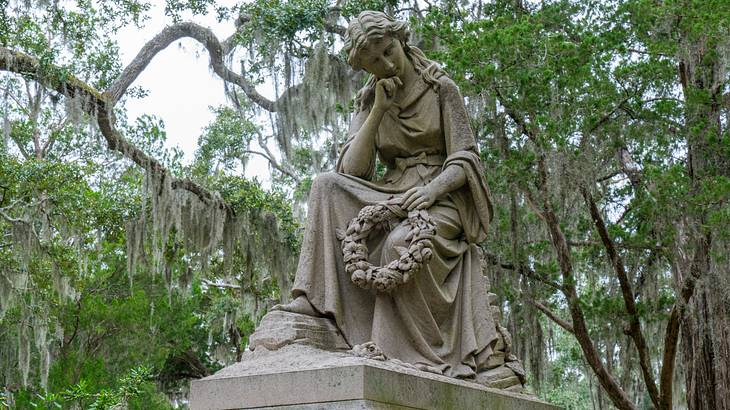 A tomb with a statue of a woman on top and trees surrounding it