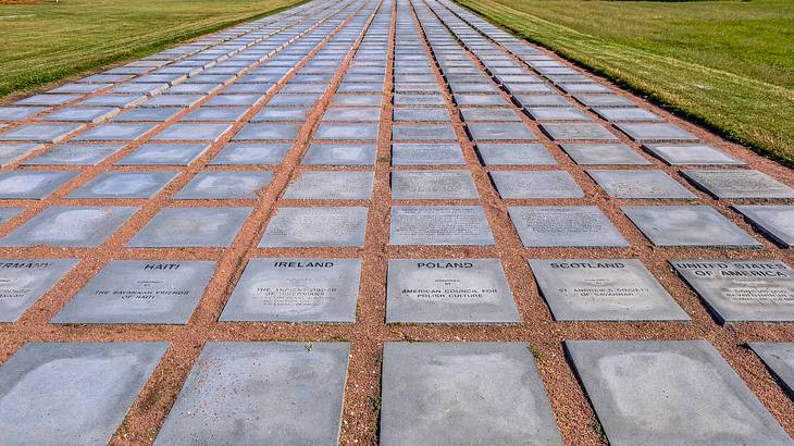 Square grey stones with engravings fixed to the ground surrounded by grass