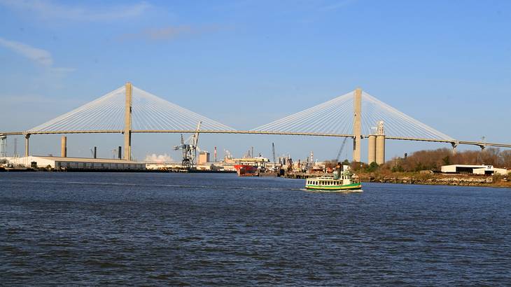 A suspension bridge with two beams with water and boats in front of it