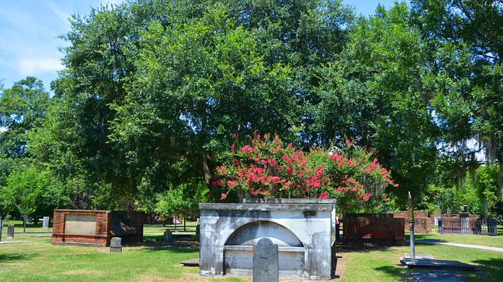 Gravestones and tombs on the grass with trees behind them