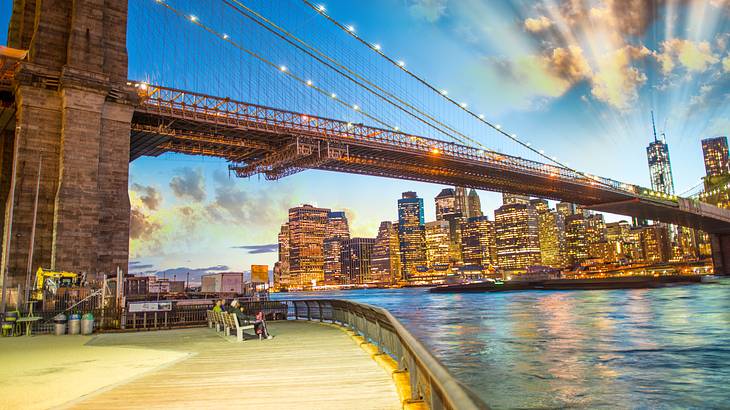 A suspension bridge over water with a boardwalk on one side and skyline on the other