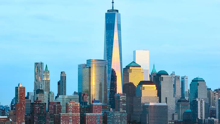 One World Trade Center surrounded by other skyscrapers with water in front