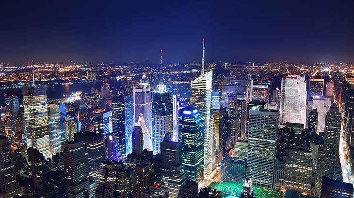 Nighttime aerial view of NYC with skyscrapers lit-up under a dark sky