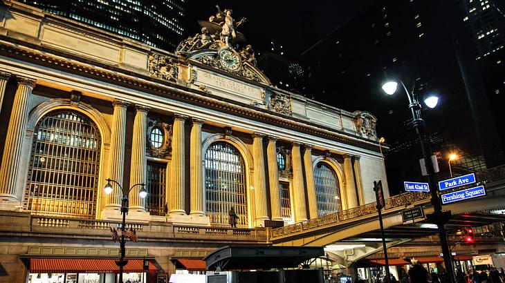 A historic building lit up at night, with a glass building behind it