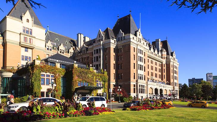 A castle-styled building next to a road, greenery, and flowers