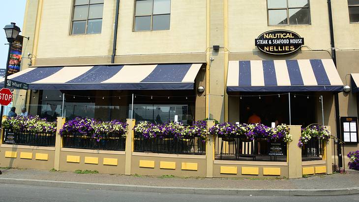 A building with blue and white awnings and a "Nautical Nellies" sign