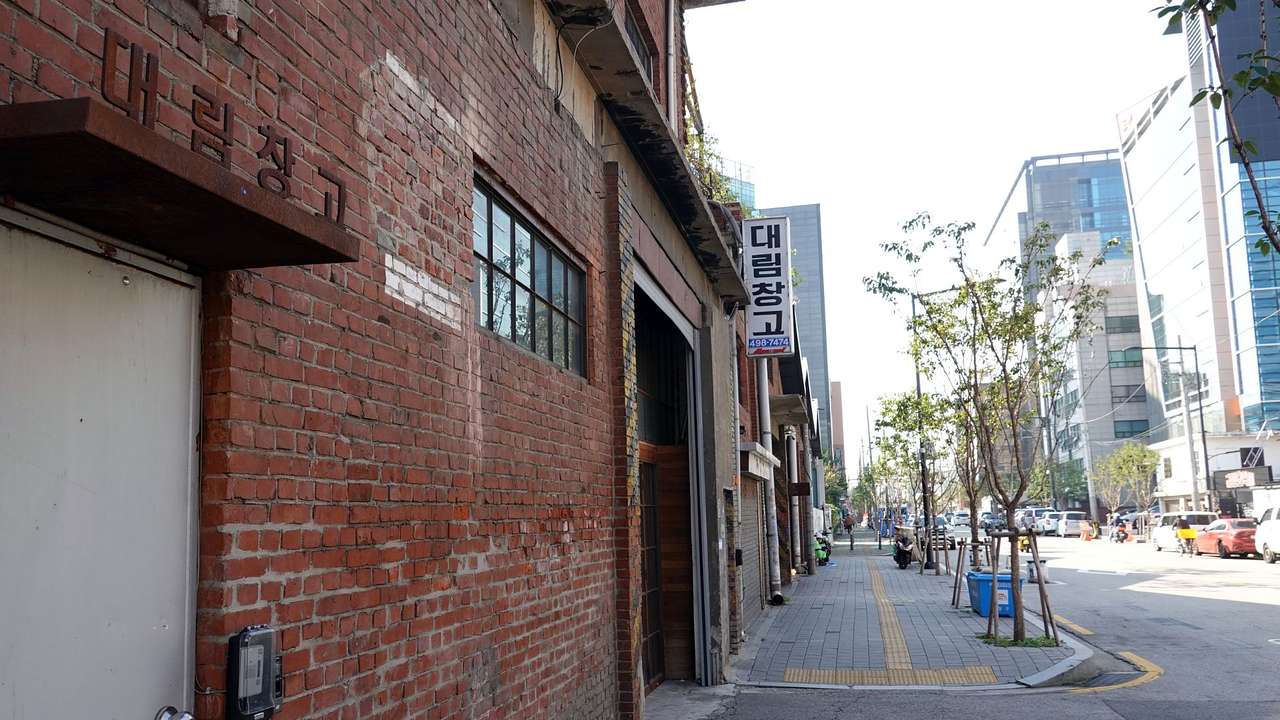 A brick building with Korean signs next to the street and a road