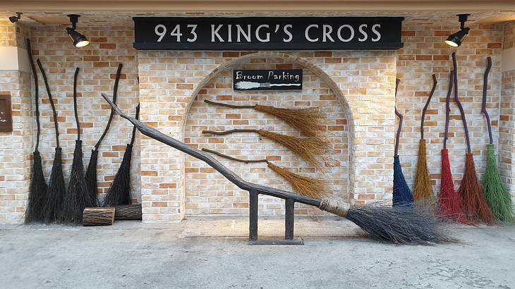 Large broomsticks next to a brick wall with a "943 King's Cross" sign