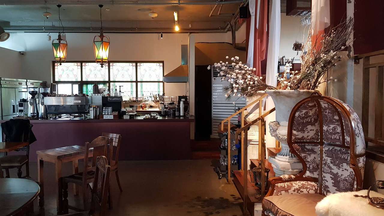 The interior of a cafe with a counter at the back and chairs and tables in front