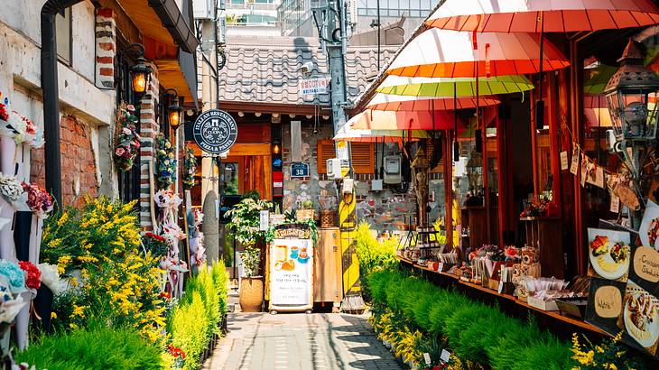 A street with shops decorated with umbrellas, plants, flowers, and souvenirs