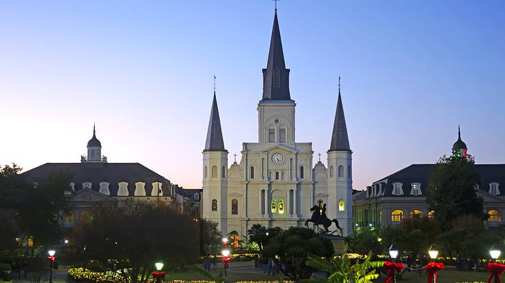 A white and black castle-style cathedral at night surrounded by a park