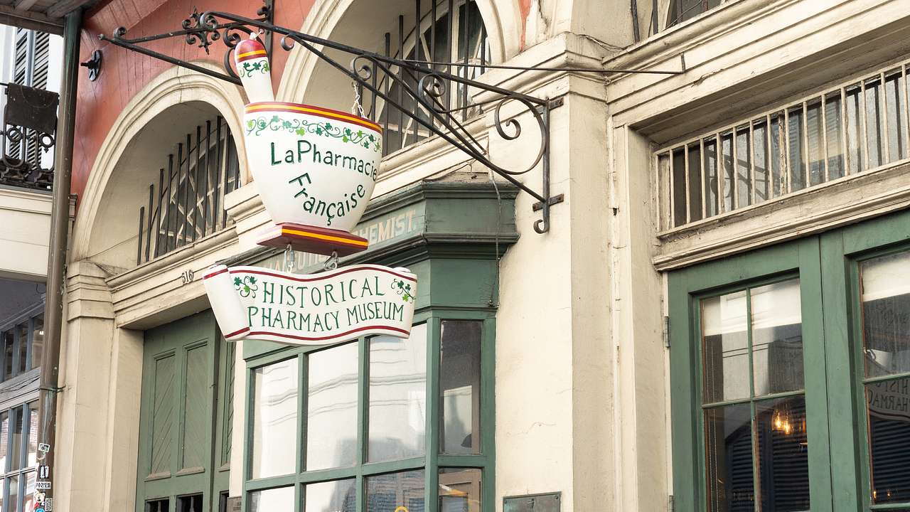 A shop with a hanging signboard designed in the shape of a mortar and pestle