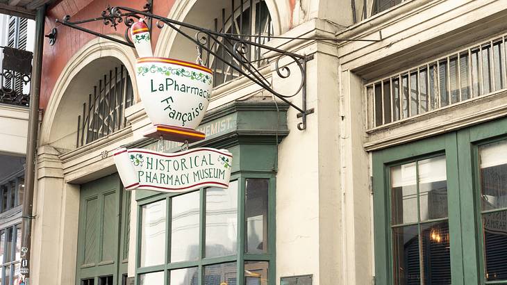 A shop with a hanging signboard designed in the shape of a mortar and pestle