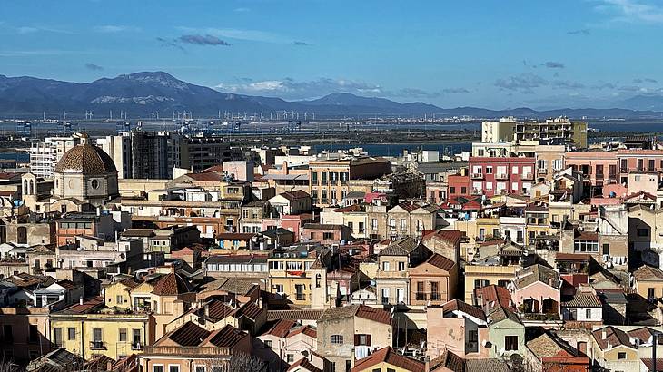 Many colourful houses with a blue sky and hills in the back, Cagliari, Italy