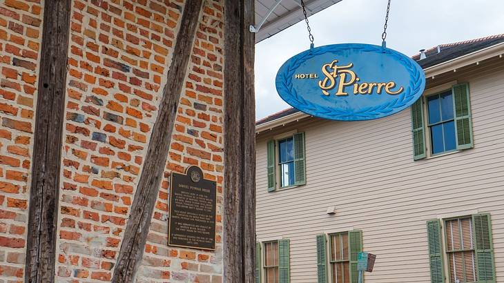 Edge of a brick house with a blue signboard that reads "Hotel St Pierre"