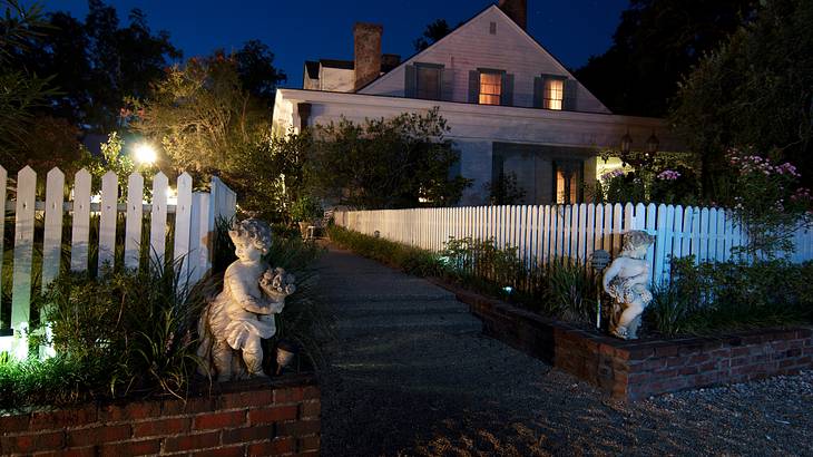 A White House with a white fence and statues in front at night