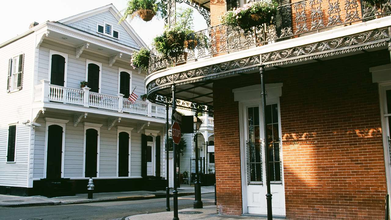 An old brick building with an iron balcony and an old white building on a street