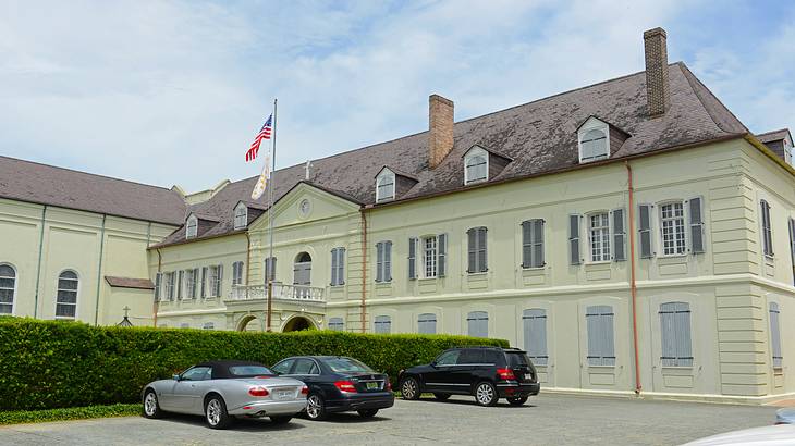 An old-fashioned tiled roof house, with landscaping and cars parked in front