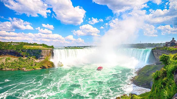 A large waterfall with water below it and a boat sailing into it