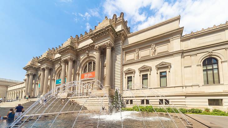 A large museum building with a water fountain in front