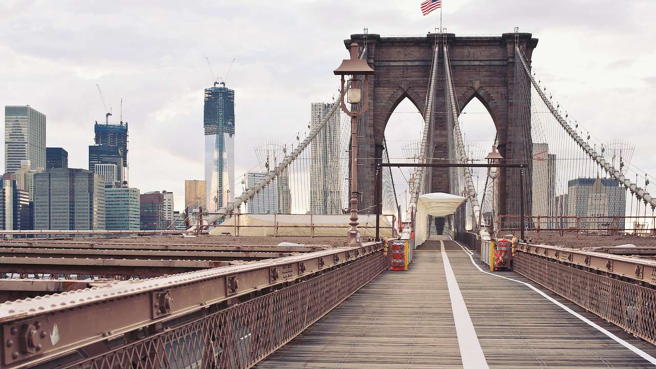 A pedestrian bridge with American flag and city skyline in the background