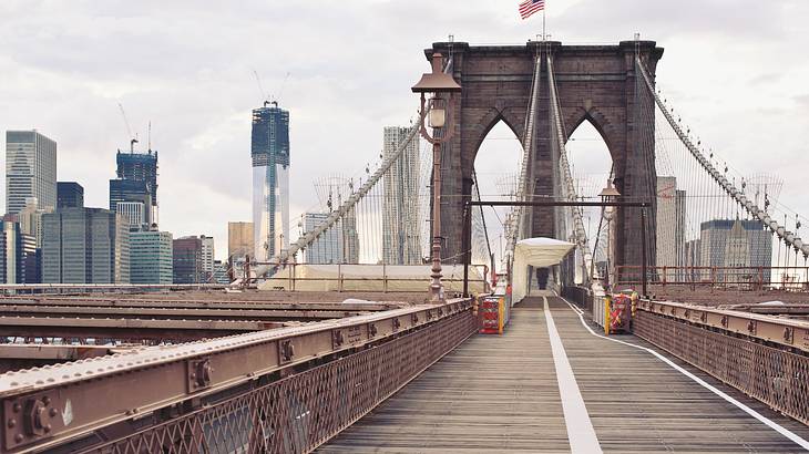 A pedestrian bridge with American flag and city skyline in the background