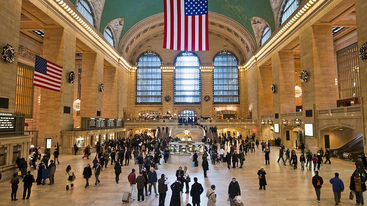 An old station building with people and an American flag hanging from the ceiling