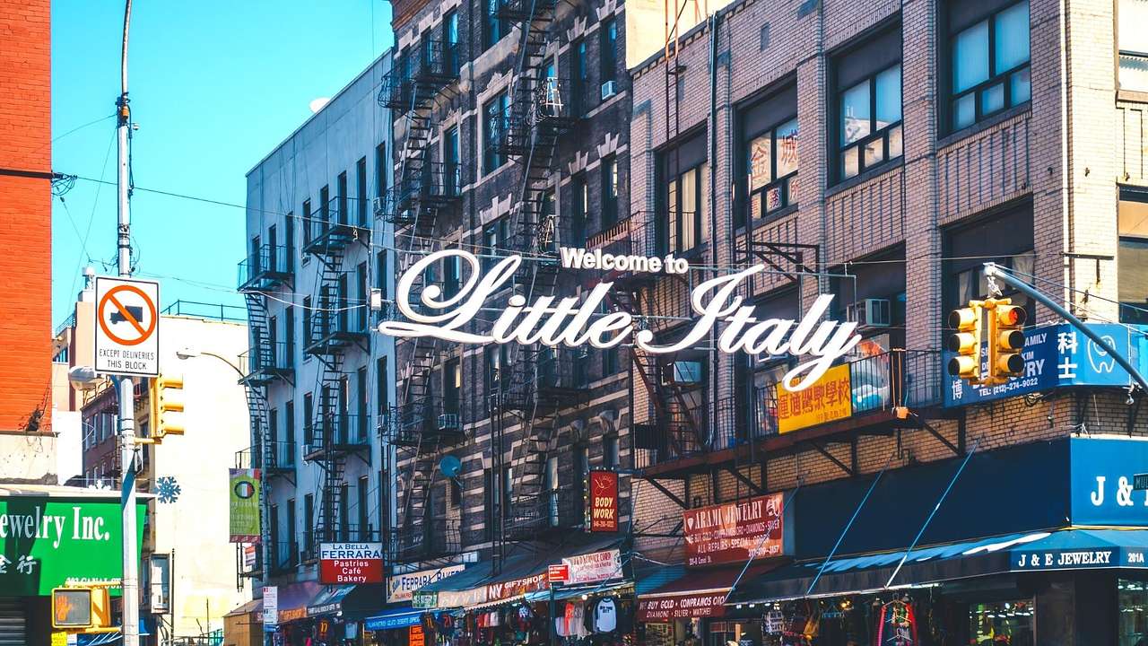 Buildings on a street with a "Welcome to Little Italy" sign across it