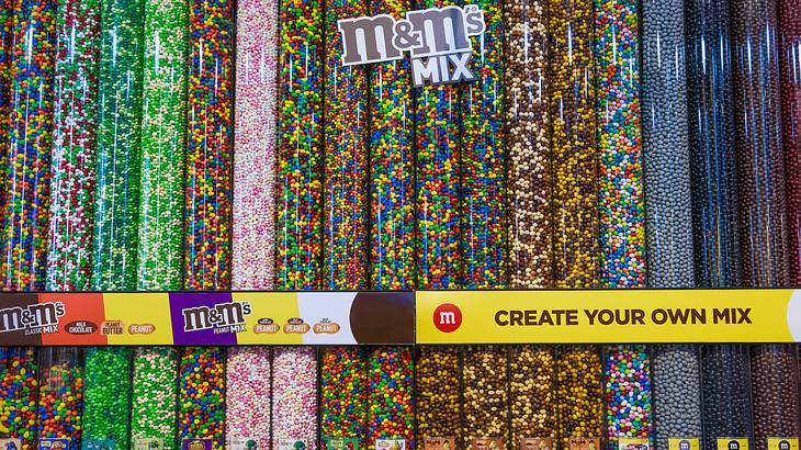 Large cylindrical containers filled with candy and "M and M's Mix" sign