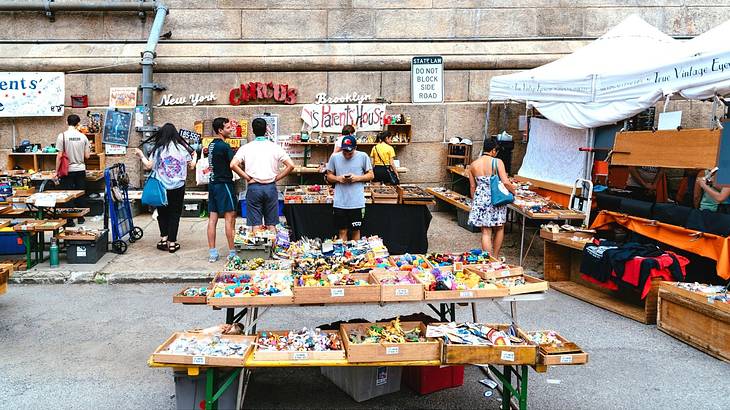 A flea market with items on tables and people looking around