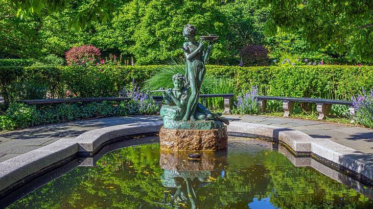 A pond with a statue and greenery surrounding it