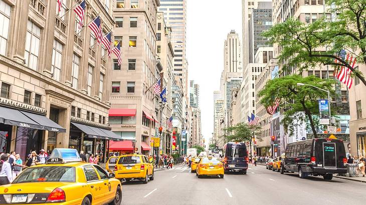 A city street with yellow taxi cabs and buildings on either side of the road