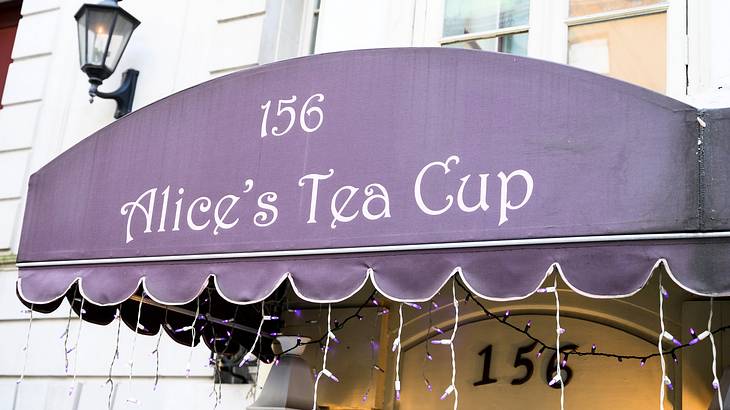 A building with a purple awning above the door with the words "156 Alice's Tea Cup"
