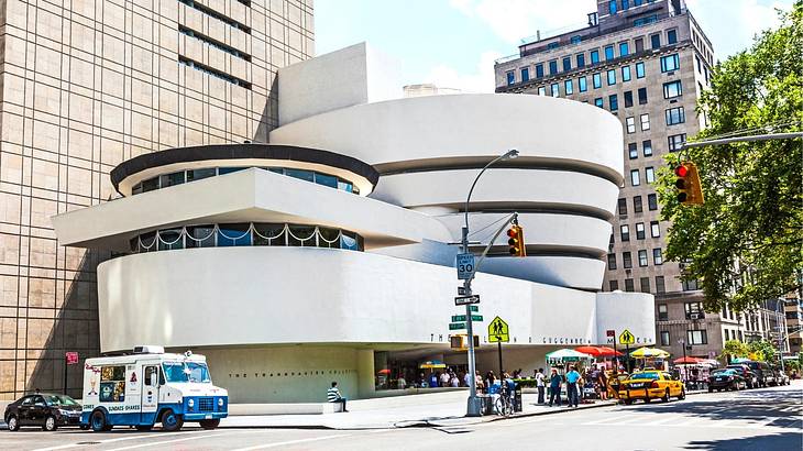 A modern museum building with a street and cars in front of it