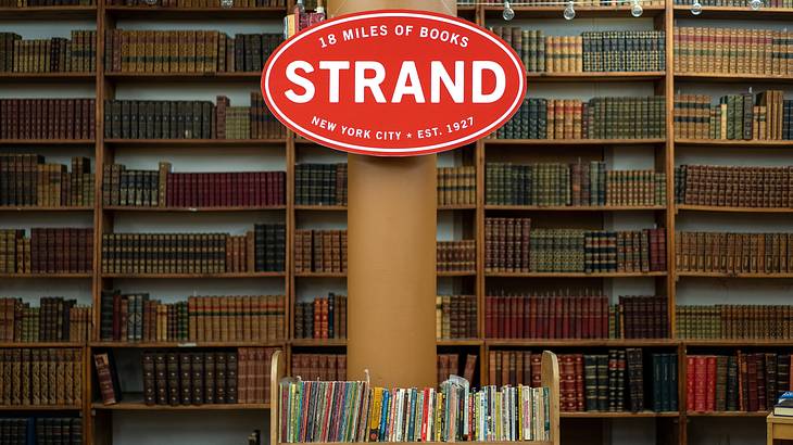 A bookstore filled with books on shelves and a red signboard in the centre