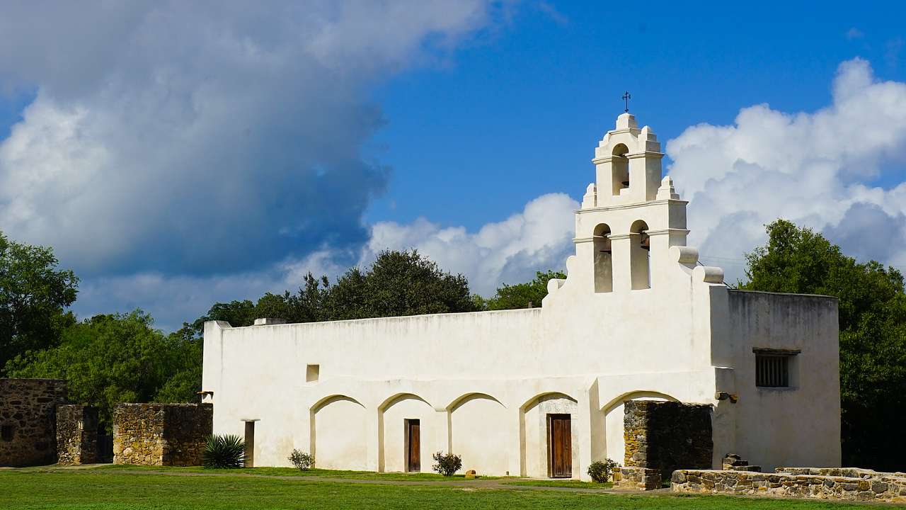 A white adobe church near a lawn on a sunny day