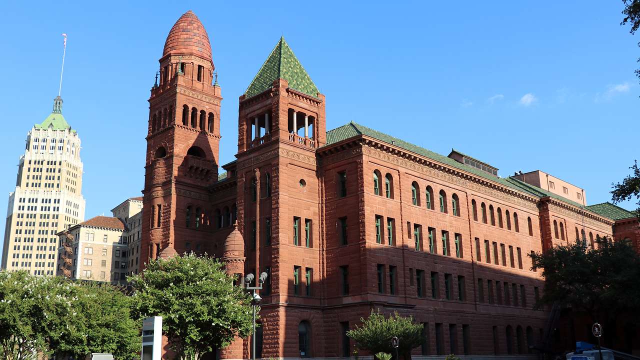 A red brick building with spires in front and a green roof