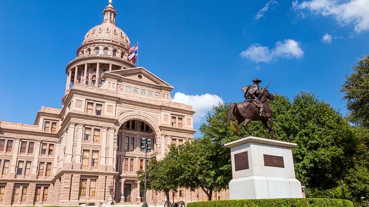 A bronze statue of a man riding a horse near a Renaissance Revival-style building