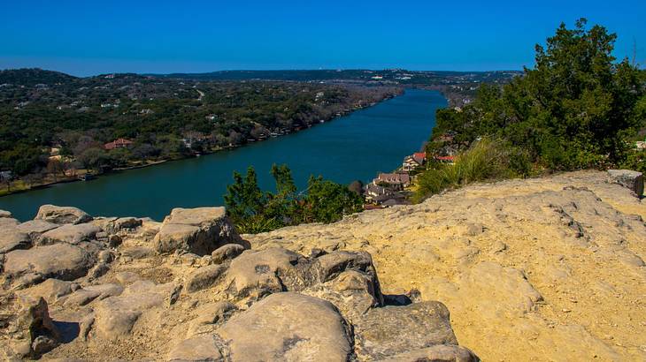 A top of a mountain overlooking a river and a rural area