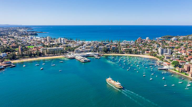 A cove with ships and boats near a city under a blue sky