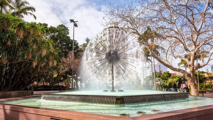 A modern-designed fountain near trees