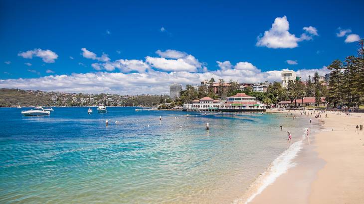 People swimming on a beach near beachside buildings