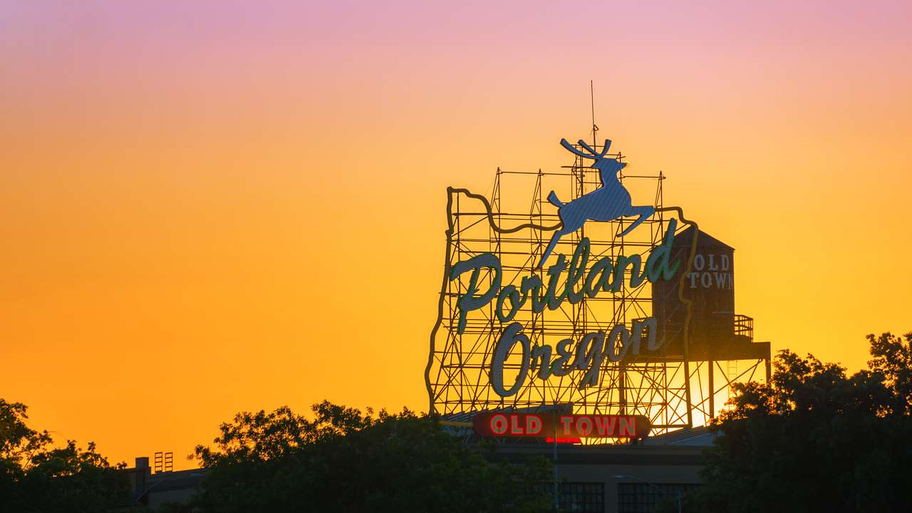 A sign saying "Portland, Oregon: Old Town" and an old water tank tower during sunset